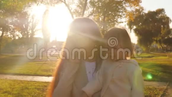 商务女性穿着商务套装带着小宝宝在智能手机上聊天在夕阳下的秋天公园散步视频的预览图