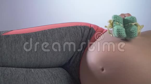 一位孕妇躺在床上肚子上放着婴儿鞋视频的预览图