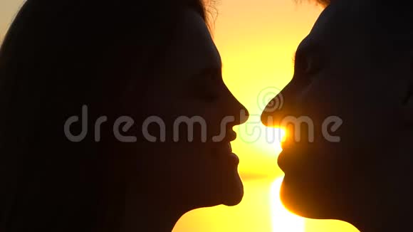 年轻浪漫夫妇的剪影两个情人年轻的男人和女人在海洋亲吻海上日落特写镜头信任爱视频的预览图