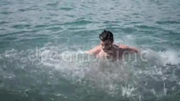 英俊的年轻男子在海里泼水视频的预览图