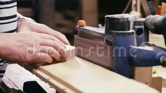 木工车间配合打磨机工作的工匠双手特写视频的预览图