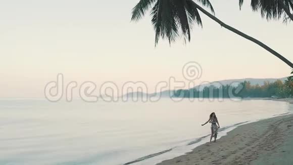快乐的女孩走在海边的沙滩上视频的预览图