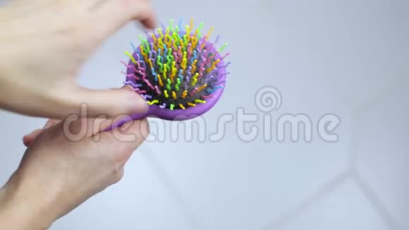 女性的手从梳子上取下掉下来的头发视频的预览图