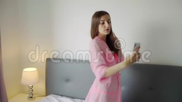 穿着透明粉红色长袍的女孩在床上自拍屁股4k视频的预览图
