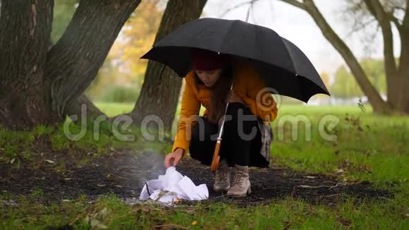 女人在多风的秋天公园里试着在雨中生火视频的预览图