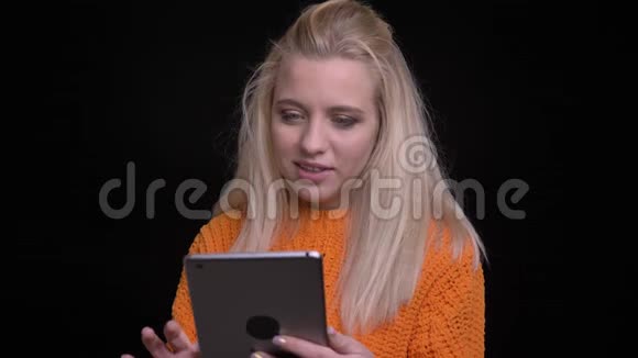 年轻漂亮的白种人女性在平板电脑上打字的特写镜头然后看着相机微笑着视频的预览图