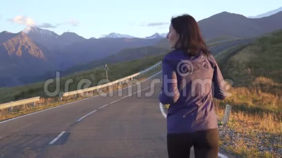 女孩运动员在日落时在去山的路上奔跑视频的预览图