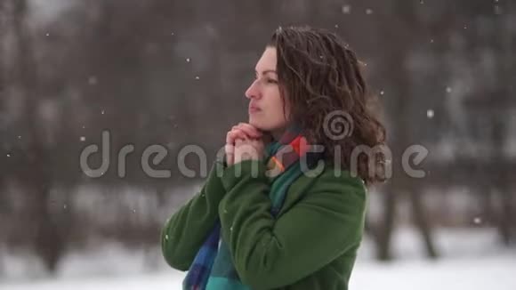 冬天美丽的卷发女孩的肖像女人是冰冷温暖的双手呼吸视频的预览图