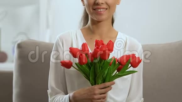 美丽的女人捧着红色郁金香花束微笑着庆祝节日视频的预览图