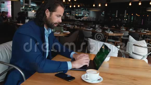 年轻的欧洲商人坐在咖啡馆里的一张桌子旁在咖啡休息时用笔记本电脑打字视频的预览图