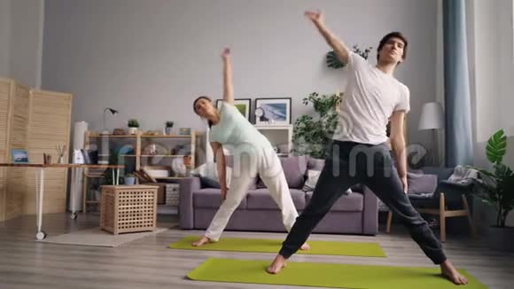 穿运动服装的男人和女人在现代公寓里做瑜伽视频的预览图