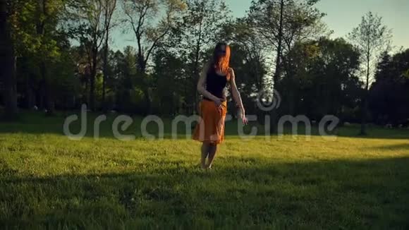 一个英俊的年轻女孩在公园里跳着舞视频的预览图
