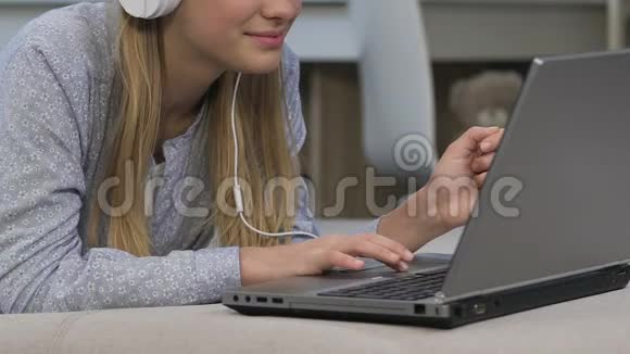 女孩在耳机听音乐和网上购物寻找购买视频的预览图