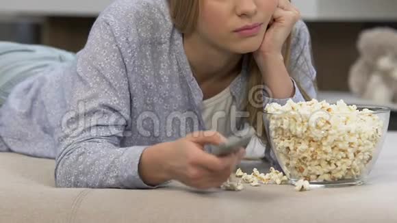 女孩吃爆米花看无聊的电视节目电视消费主义视频的预览图