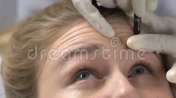 美容师在填充剂注射前标记前额皱纹皮肤完美视频的预览图