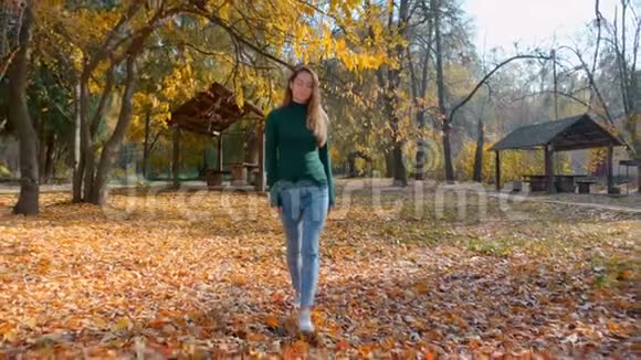 秋天一个年轻漂亮的黑发女人正在公园里散步公园的背景是黄树视频的预览图