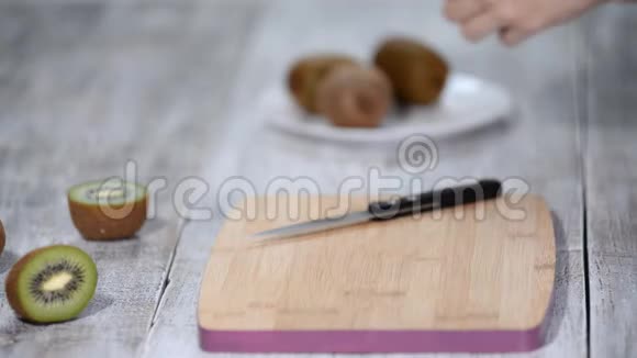 一个女人用一把刀在木头背景上清洗猕猴桃皮视频的预览图