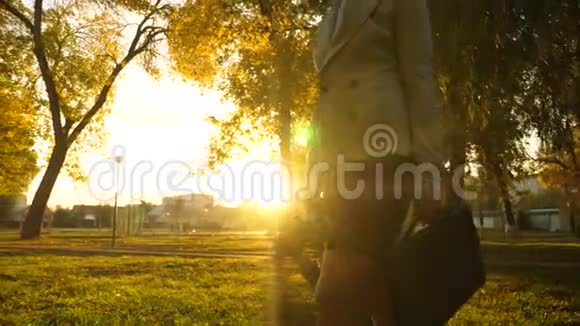 女人手里拿着公文包在阳光明媚的公园里沿着人行道走着特写镜头视频的预览图