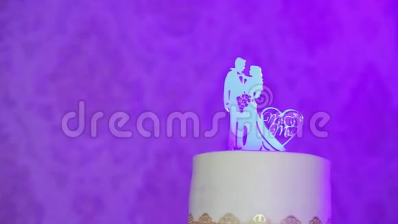 装饰精致的金属小新郎雕像新娘穿着婚纱在蛋糕的上方反射光线视频的预览图