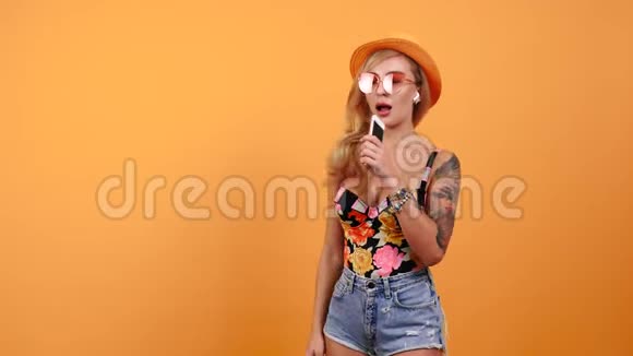 戴着帽子在手机里唱歌的性感女人的肖像视频的预览图