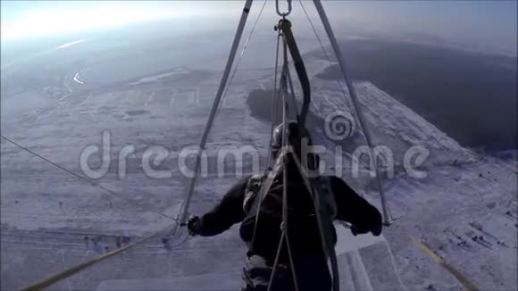 悬挂滑翔机在阳光明媚的天空中飞过白雪覆盖的草地视频的预览图