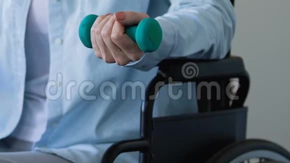 坐在轮椅上的妇女中风后试图发展手臂举起哑铃视频的预览图
