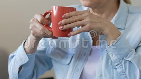 老年妇女享受着完美的早晨啜饮着茶望着窗外视频的预览图