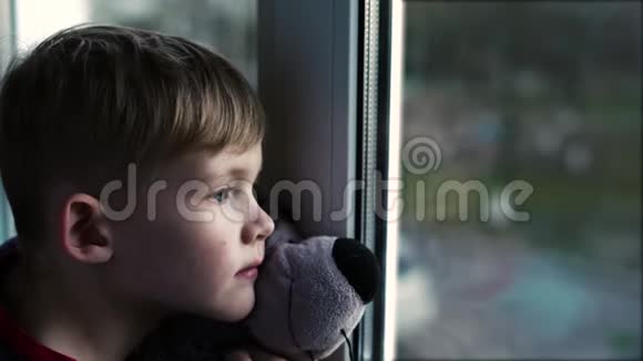悲伤的小男孩孤独的小男孩小男孩近看窗外视频的预览图