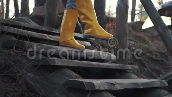 穿着黄色橡胶靴和蓝色牛仔裤的人腿走在室外的木制楼梯上双脚穿着橡胶靴视频的预览图