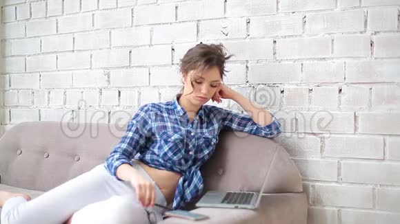 女自由职业者戴上眼镜开始在家里用笔记本电脑工作她穿着白色牛仔裤和蓝色格子呢视频的预览图