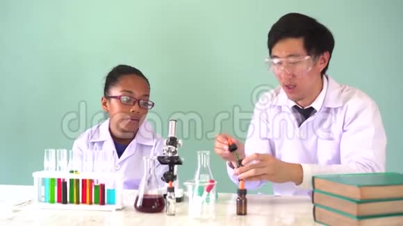 年轻的科学家拿着一个烧瓶在化学实验中教非裔美国人混合孩子视频的预览图