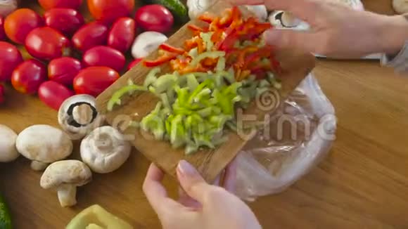 女人手把切红和青椒放在一个塑料包装里冷冻在厨房的桌子上视频的预览图
