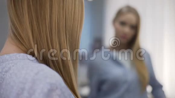 年轻女性在房间镜子附近梳理光滑的头发保湿洗发水视频的预览图