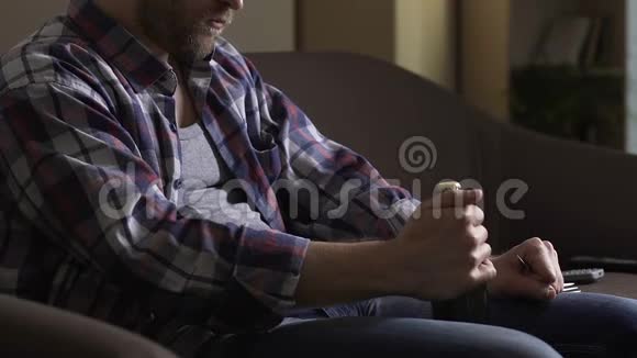 单身男人坐在沙发上试图用叉子打开啤酒瓶绝望视频的预览图