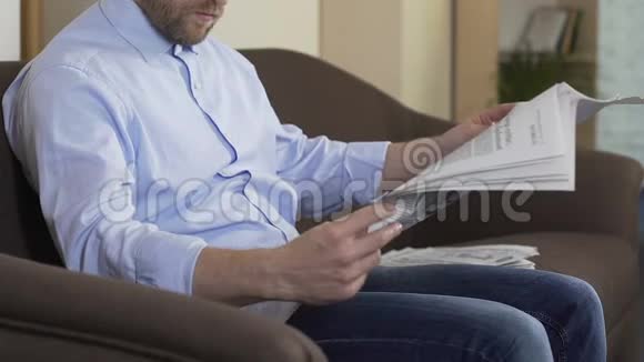 成年人坐在沙发上在家看报纸时事休闲视频的预览图