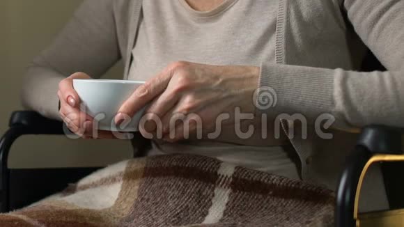成熟的女人坐在靠窗的轮椅上喝着热茶视频的预览图
