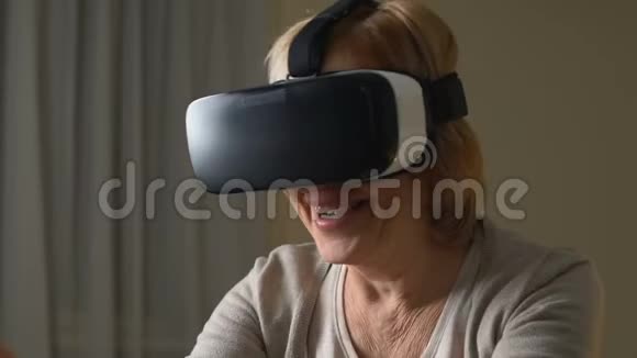 令人兴奋的老年妇女喜欢使用虚拟现实眼镜和现代技术视频的预览图