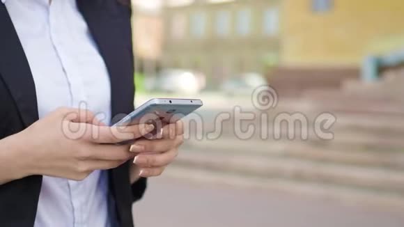 女人在街上用她的智能手机特写人手握科技设备浏览互联网和视频的预览图