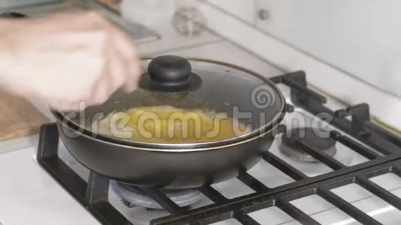 男人手打开煤气炉上的煎锅里用香肠准备炒鸡蛋的盖子视频的预览图