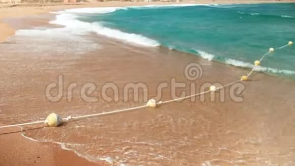 海浪在海滩上翻滚在漂浮的浮标上断裂的4k慢镜头视频的预览图