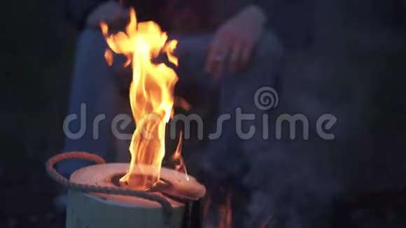 一个人坐在篝火旁手里拿着一根棍子在森林里的火边抽烟的人视频的预览图