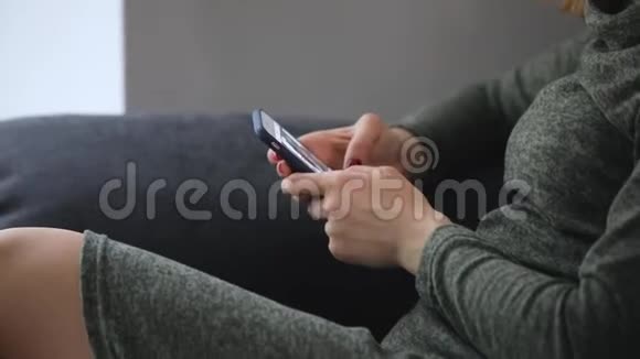 女人在社交网站上浏览智能手机坐在舒适的沙发上视频的预览图