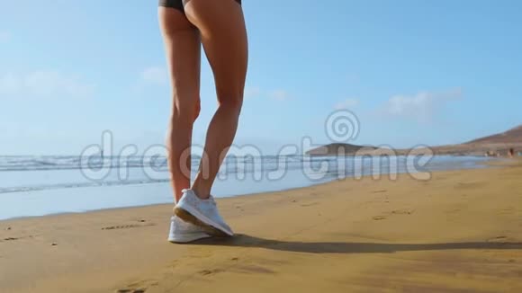 在美丽的沙滩上奔跑的穿着白色运动鞋健康的慢动作生活方式的腿部运动女性特写镜头视频的预览图