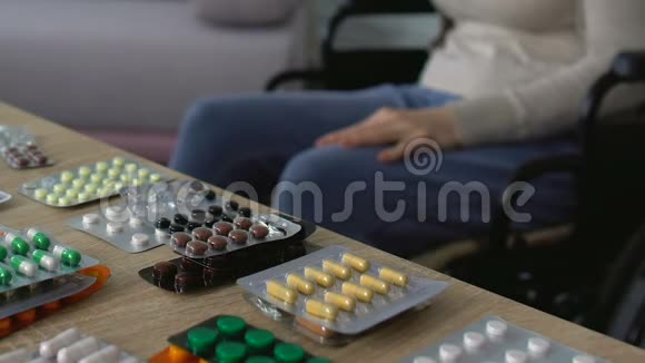 一位坐在轮椅上的老太太坐在靠近桌子的地方医院里有很多药片视频的预览图