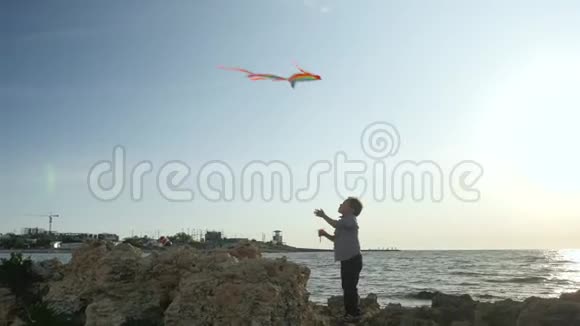 儿童体育游戏小男孩控制着放五颜六色的风筝天空乌云太阳暑假视频的预览图