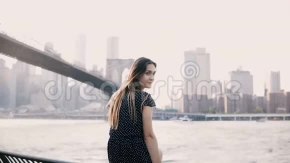 镜头接近美丽的欧洲女孩回首和微笑坐在纽约布鲁克林大桥全景视频的预览图