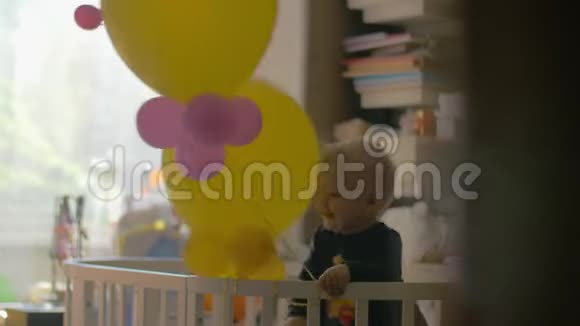 小女孩在婴儿床上玩气球视频的预览图