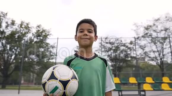 微笑的男孩带着足球看着相机视频的预览图
