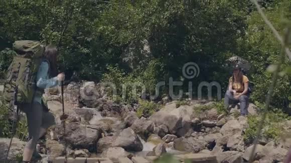 在山上的石河上走在木桥上的旅行妇女视频的预览图
