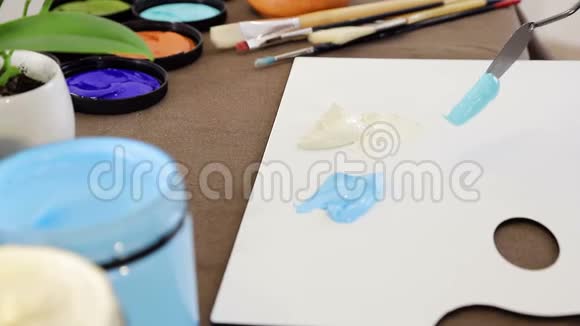 艺术家在调色板上放一个蓝色的油漆刮刀来混合颜色视频的预览图